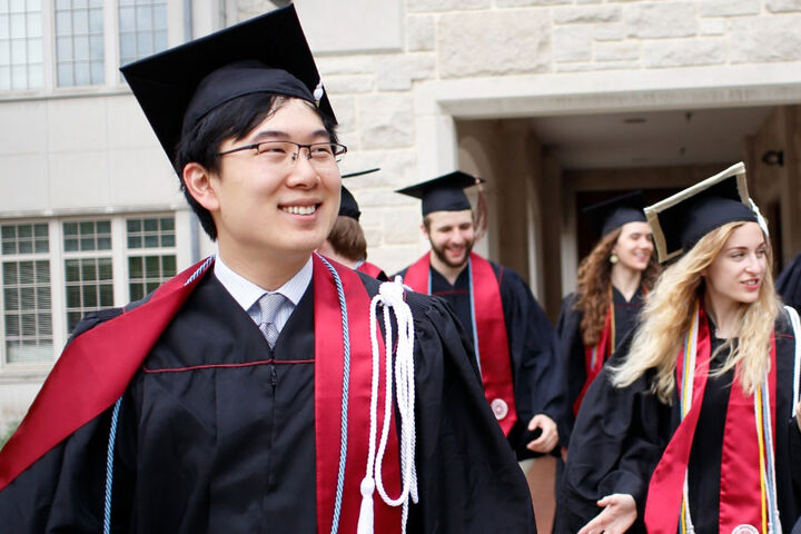 Smiling graduates walk outside of a building at IU Bloomington.